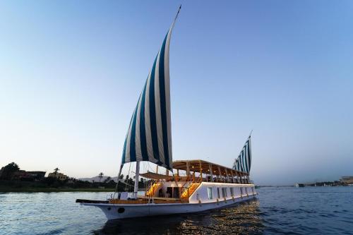 a boat with a large sail on the water at Turquoise in Luxor