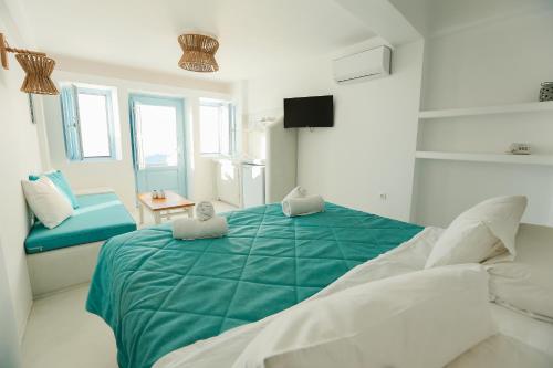 a white bedroom with a green bed and a chair at Ilioperato Hotel in Imerovigli