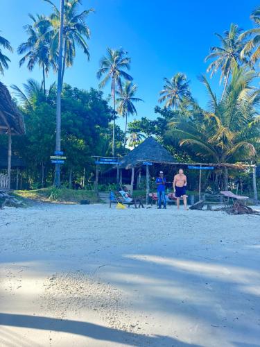 duas pessoas numa praia com palmeiras em Juani beach bungalows em Kilindoni