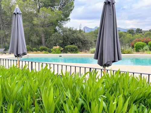 deux parasols gris assis à côté d'une piscine dans l'établissement SUITE Supérieure Domaine du Golf St Endreol, 1 à 2 personnes, à La Motte