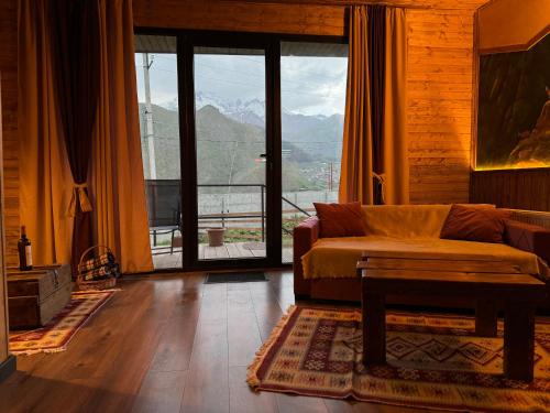 a living room with a couch and a large window at Checkin Kazbegi in Stepantsminda
