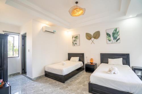 two beds in a room with white walls at Beach Palm Villa Hoi An in Hoi An