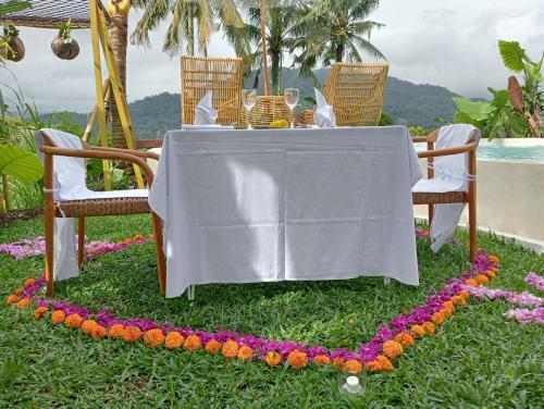 a table with a white table cloth and flowers on the grass at Gladak di Uma Bali in Sidemen