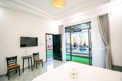 a room with a table and chairs and a television at Beach Palm Villa Hoi An in Hoi An