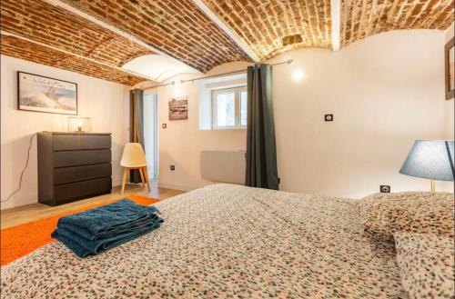 une chambre avec un lit et un mur de briques dans l'établissement Le Duplex du BIPLAN, à Lille