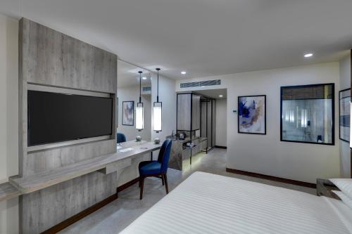 a bedroom with a bed and a desk with a television at Karachi Marriott Hotel in Karachi