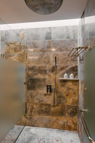 a bathroom with a shower with a stone wall at Rosee Villa - Green Villa with private Pool in Vĩnh Phúc