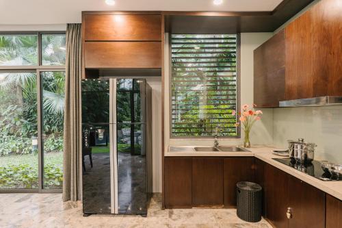 a kitchen with wooden cabinets and a large window at Rosee Villa - Green Villa with private Pool in Vĩnh Phúc