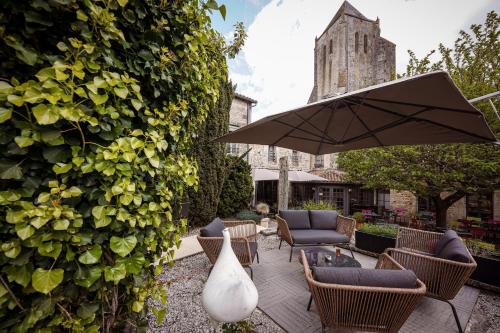 a patio with chairs and a table and an umbrella at Logis Hostellerie de l'Abbaye in Celles-sur-Belle