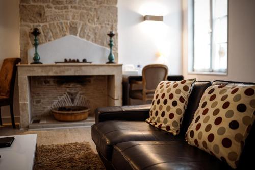 a living room with a leather couch and a fireplace at Logis Hostellerie de l'Abbaye in Celles-sur-Belle