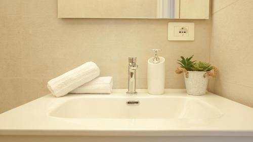 a bathroom sink with a soap dispenser and a plant at Postcard in Alghero