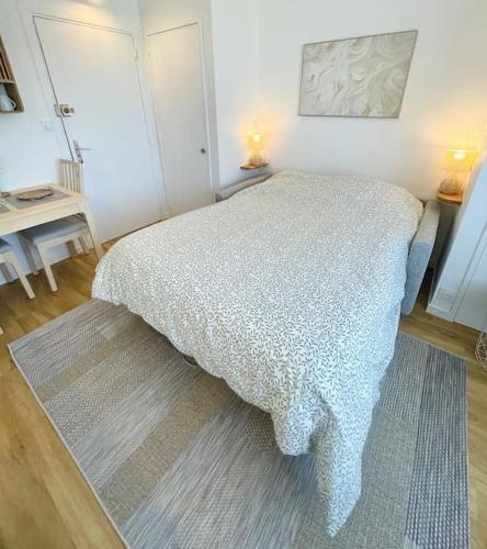 a bedroom with a bed with a blanket on it at Confortable studio à 2min de la plage et du centre in Cabourg