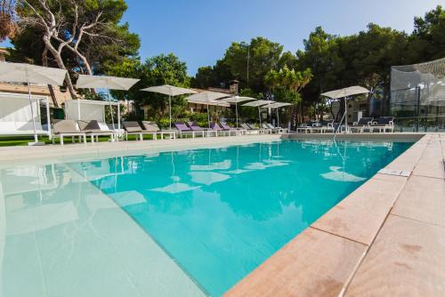 a large swimming pool with chairs and umbrellas at Flacalco Hotel & Apartments in Cala Ratjada