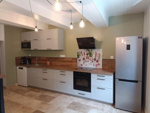 une cuisine avec des armoires blanches et un réfrigérateur blanc dans l'établissement Maison de village avec parking à 5 min de Vaison La Romaine, à Puyméras