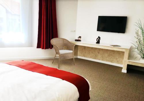 a bedroom with a bed and a desk with a television at Csiki Hotel in Miercurea-Ciuc
