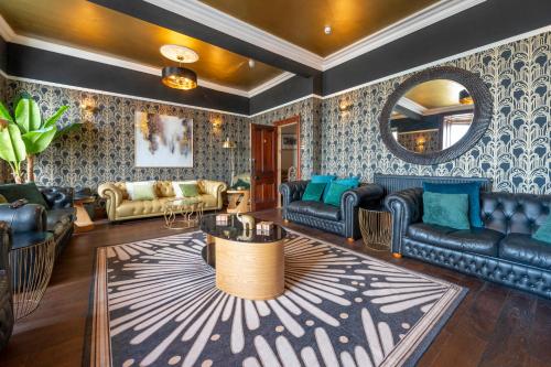 a living room with leather furniture and a mirror at The Belmont Barmouth in Barmouth