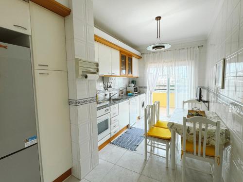 a kitchen with white cabinets and a table and chairs at Plaza Real - Silhueta Citadina in Portimão