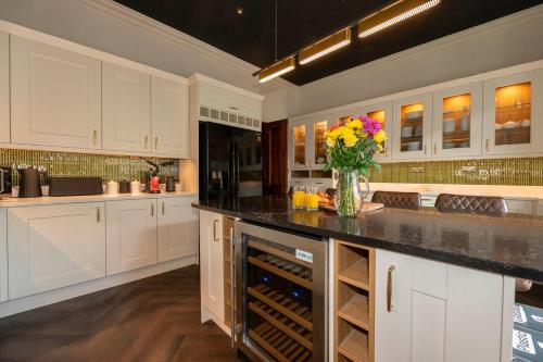 a kitchen with white cabinets and a vase of flowers at The Belmont Barmouth in Barmouth