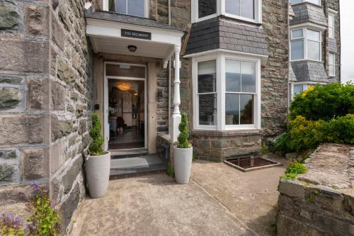a brick house with two white vases on the front door at The Belmont Barmouth in Barmouth