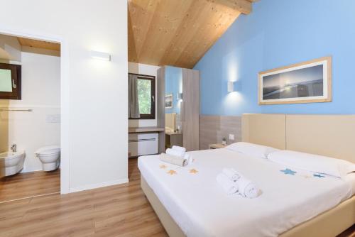a bedroom with a large white bed and a bathroom at Paradù EcoVillage & Resort in Marina di Castagneto Carducci
