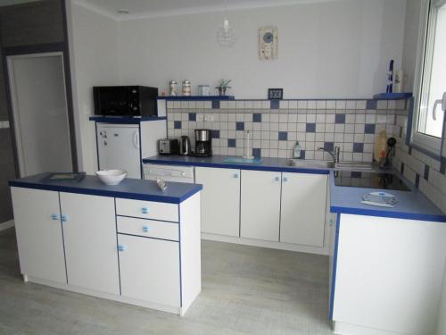 eine Küche mit weißen Schränken und blauen Arbeitsplatten in der Unterkunft Maison 6 pers - 3ch à Saint Hilaire de riez classé 3 Etoiles in Saint-Hilaire-de-Riez