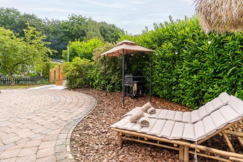 a patio with a couch and an umbrella at Hotel chique tiny wellness hottub & sauna in Voorthuizen