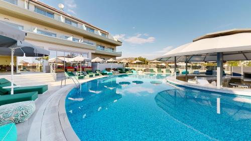a pool with chairs and umbrellas next to a hotel at The Dome Luxury in Limenaria