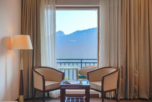 a room with two chairs and a table and a large window at The Sanawar Heights I Kasauli I New Property in Kasauli