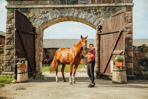 a woman leading a horse out of a gate at Brīvdienu māja ''Rātes'' Valmiermuiža in Valmiermuiža