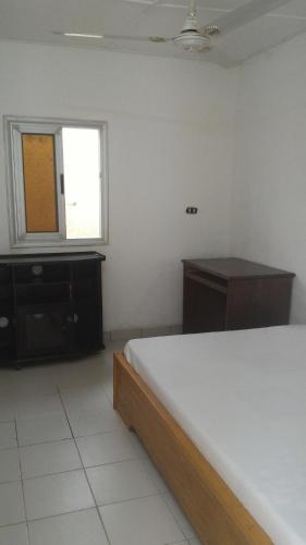 a bedroom with a bed and a dresser and a window at Residence Diane in Ouagadougou