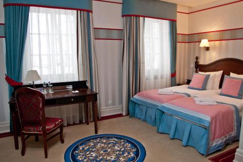 a hotel room with two beds and a desk and window at Hotel St. Bruno in Giżycko
