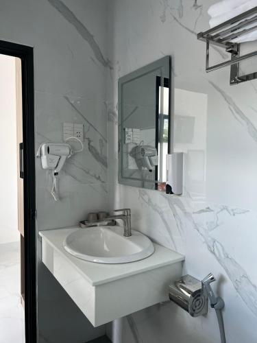 a white bathroom with a sink and a mirror at Nhà nghỉ Pha Lê in Cao Lãnh