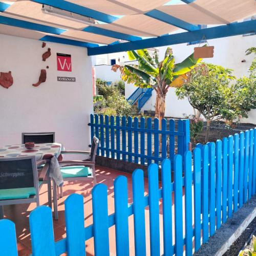 a blue picket fence with a table and chair in a patio at vivienda vacacional Alipatri in Caleta De Fuste