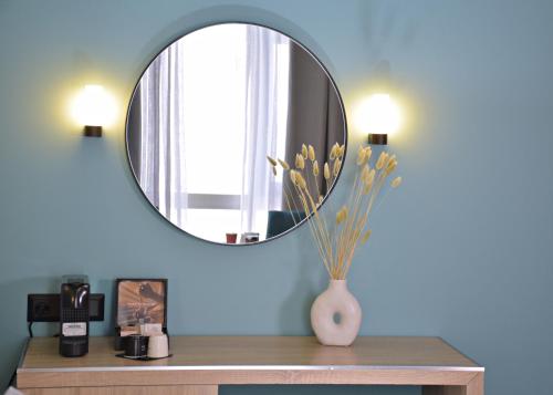a mirror on a wall above a table with a vase with flowers at Arethusa Hotel Athens in Athens