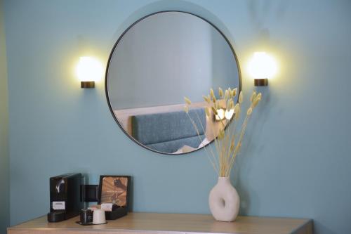 a mirror on top of a table with a vase with flowers at Arethusa Hotel Athens in Athens
