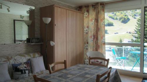 une salle à manger avec une table et une grande fenêtre dans l'établissement Appartement à GOURETTE, résidence EURONEIGE, avec balcon, vue idéale sur la montagne - 6 personnes, à Eaux-Bonnes