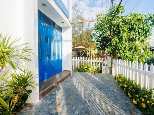 a house with a blue door and a white fence at Lee House Villa Tam Thanh in Tam Ky