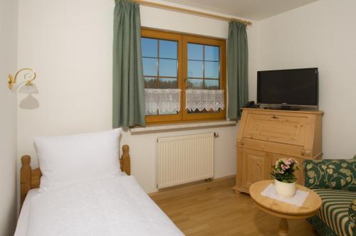 a bedroom with a bed and a tv and a couch at Landhotel Jungbrunnen in Bad Brambach