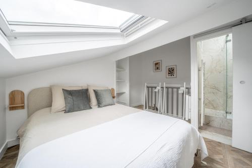 une chambre blanche avec un lit blanc et une fenêtre dans l'établissement La Versaillaise Bucolique - Stationnement privatif - Proche Gare Chantiers, à Versailles