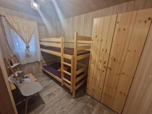 a small room with a bunk bed and a chair at POD SOSNAMI Ośrodek Wypoczynkowy Boszkowo Letnisko in Boszkowo