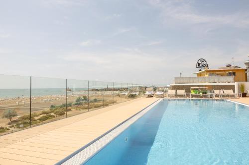 einen großen Pool mit Blick auf den Strand in der Unterkunft Hotel Monaco in Caorle