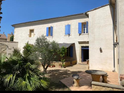 a large white building with blue windows and a courtyard at Le Figuier in Beauvoisin