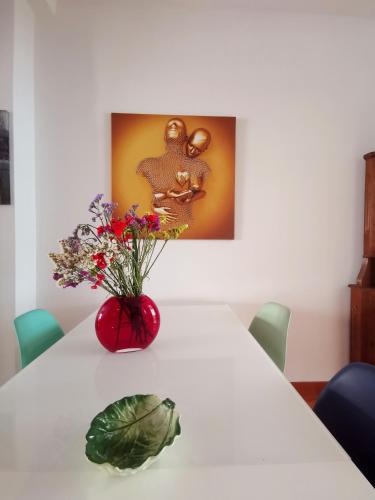 a red vase with flowers on a white table at Cipro Home in Rome