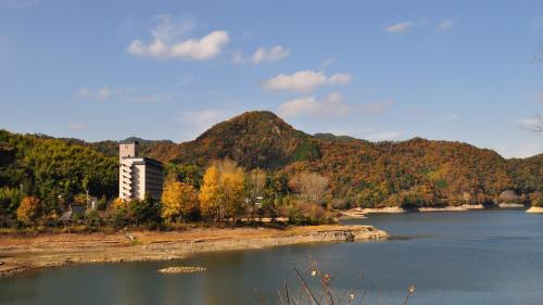 a view of a lake with a building and a mountain at Hyper Resort Villa Shionoe in Shionoe