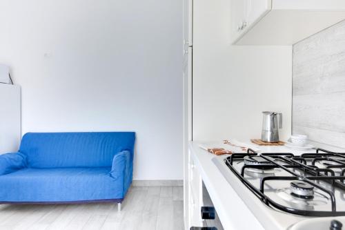 a blue couch sitting next to a stove in a kitchen at Residence Diffuso Arcobaleno in Gabicce Mare