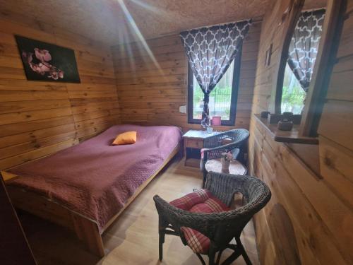 a small bedroom with a bed and two chairs at POD SOSNAMI Ośrodek Wypoczynkowy Boszkowo Letnisko in Boszkowo