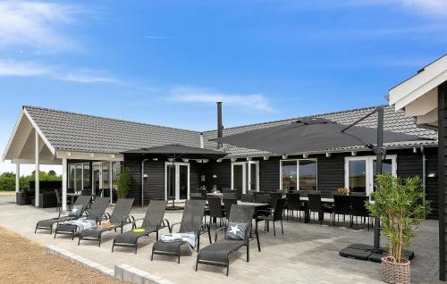 a patio with black chairs and tables and umbrellas at Gorgeous Home In Bogense With Sauna in Bogense