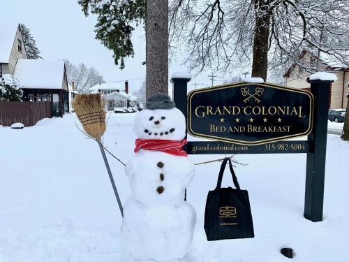 a snowman in front of a sign in the snow at Grand Colonial Bed and Breakfast in Herkimer