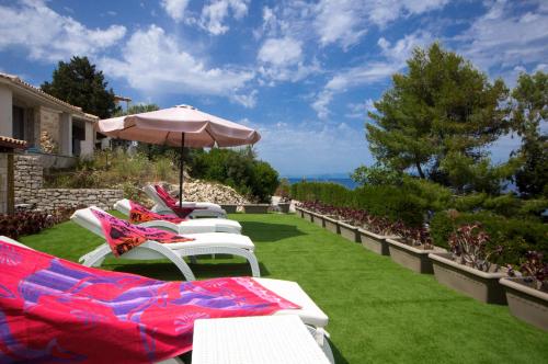 a row of white lounge chairs with an umbrella at Villa Baronnos in Gaios