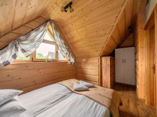 a bed in a wooden room with a window at Domki "Na Dziedzinie" z Gorącą Balią in Szaflary